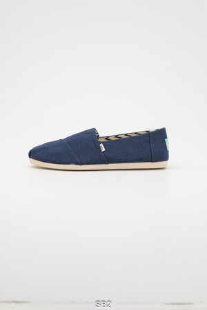 Chaussure en toile bleu marine à enfiler avec un bout arrondi, une semelle en caoutchouc beige et un intérieur à motifs. Dispose d'une petite étiquette de marque sur le côté.