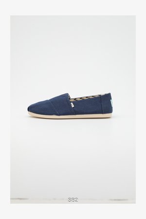 Chaussure en toile bleu marine à enfiler avec un bout arrondi, une semelle en caoutchouc beige et un intérieur à motifs. Dispose d'une petite étiquette de marque sur le côté.