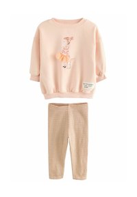 Ljusrosa sweatshirt med grafiskt mönster av en tjej och hund, i kombination med beige rippade leggings. Mjukt, avslappnat material, lätt lös passform.