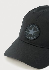 Μαύρο καπέλο μπέιζμπολ με στρογγυλό έμβλημα "Converse All Star Chuck Taylor" στην μπροστινή πλευρά.