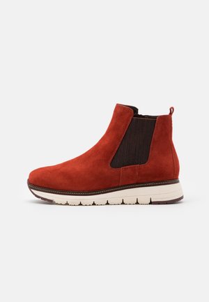 Botín de ante rojo con panel lateral elástico oscuro, suela blanca y tira para tirar, diseñado para uso casual.