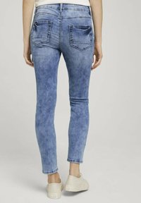 Bleka blå skinny jeans med midjehöjd, två bakfickor och smal passform, i kombination med ljusa skor.