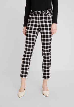 Pantaloni a scacchi in bianco e nero con un design aderente, caratterizzati da vita media, tasche laterali e taglio alla caviglia. Tessuto dalla consistenza liscia.