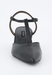 Czarny skórzany but na wysokim obcasie z szpiczastym noskiem i paskiem na kostkę. Gładka faktura, minimalistyczny design i charakterystyczna krzywa na obcasie.