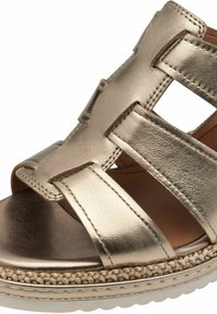 Guldmetallic kilklackssandal med korsade remmar, slät yta och en texturerad espadrille-liknande mellansula med gummiyttersula.