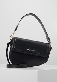 Borsa a spalla in pelle nera con design curvo, hardware dorato e chiusura a patta. Caratterizzata da una tracolla regolabile e logo stampato.