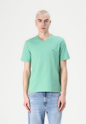 Tricou mint green cu decolteu în V, realizat dintr-un material de bumbac moale, cu mâneci scurte, având un mic logo pe pieptul stâng. Purtați-l cu blugi albaștri deschiși.