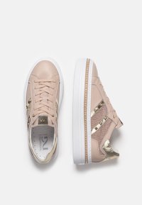 Sneakers in pelle beige con accenti dorati, pannelli laterali texturizzati, laccio frontale e suola platform bianca con decorazione intrecciata.
