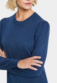 Maglione a maglia blu navy con collo a girocolo a coste e maniche corte a sbuffo, realizzato in tessuto morbido con una superficie liscia.