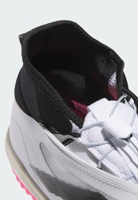 Sportliche Hochschuh mit einem schwarzen Stoffkragen, einem weißen synthetischen Oberteil, pinken Akzenten und einem elastischen Schnürsystem für einen sicheren Sitz.