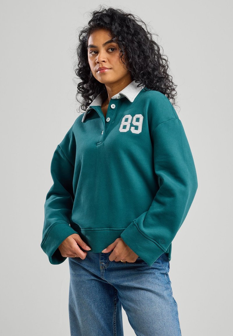 Pullover turchese con collo grigio, caratterizzato da un grande '89' bianco sul petto. Tessuto morbido, vestibilità comoda e maniche lunghe. Design casual.