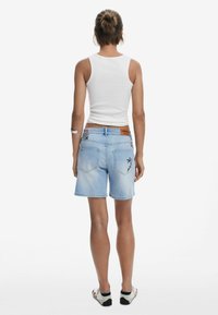 Ljusblå denimshorts med blommig broderi på bakfickorna, en brun läderpatch i midjan och en avslappnad passform.