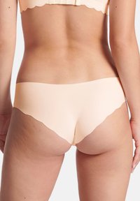 Mutande seamless color pesca chiaro con orli scallop, realizzate in materiale liscio. Il design prevede una copertura minima e una vestibilità a vita bassa.