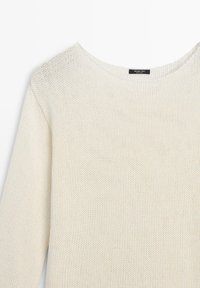 Maglione a maniche lunghe color crema con scollo rotondo e trama a maglia visibile, che mostra la parte superiore del busto.