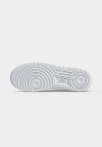 Σόλα λευκού sneaker Nike με κυκλικά και γραμμικά σχέδια πέλματος και το λογότυπο της Nike ανάγλυφο στο κέντρο.