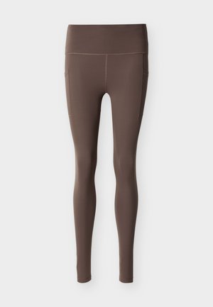 Brune leggings med høy linning, glatt tekstur og sidelommer. Har kontrasterende flatlock-søm og en tettsittende design.
