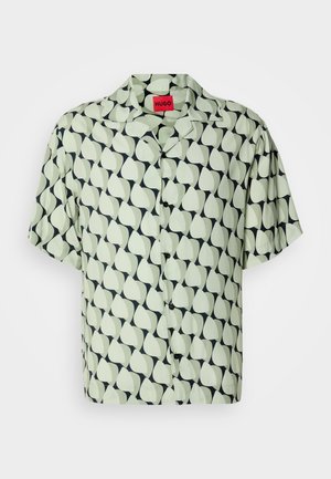 Chemise à manches courtes boutonnée en vert clair avec un motif de feuilles abstraites navy. Présente un col camp et des boutons noirs. Texture de tissu lisse.