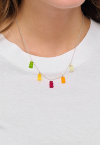 Silberne Halskette mit fünf Gummibärchen-Anhängern in Grün, Rot, Gelb, Orange und Transparent, angeordnet in einem verspielten, versetzten Design.