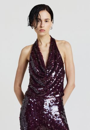 Top bordeaux con paillettes, scollo a cascata drappeggiato e design aderente. Le paillettes riflettenti creano una superficie testurizzata e lucida.