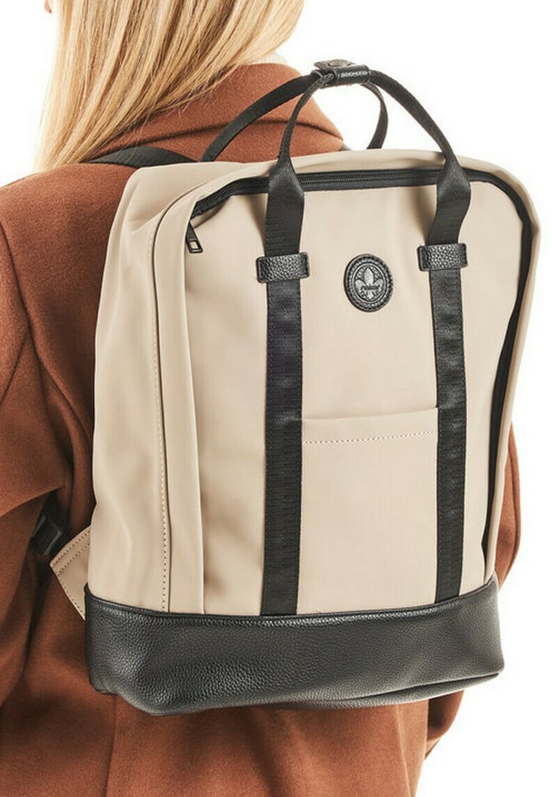 Beige rugzak met een textuur van zwart leer aan de onderkant, zwarte riemen en een ritssluiting. Voorzien van een voorvak en een rond logo.