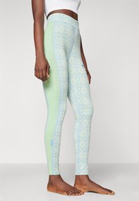 Leggings in light green with a diamond pattern in blue and white. Features a high waistband and flat seams, made from a textured fabric.