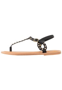 Infradito in pelle nera con design borchiato, fibbia laterale e suola piatta color beige. Presentano dettagli decorativi sulle cinghie.