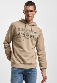 Beige Kapuzenpullover aus Baumwolle mit einem Frontdruck des Logos "JACK & JONES". Das Design umfasst eine Kapuze mit Kordelzug und gerippte Bündchen.