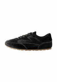 Scarpa sportiva nera realizzata in materiale morbido e testurizzato con un design elegante. Presenta lacci decorati e una suola in gomma naturale.