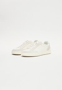Weiße Sneaker aus einer Kombination von glattem Leder und Wildleder, mit runder Zehenkappe, abgerundeten Schnürsenkeln und einer strukturierten Gummisohle.