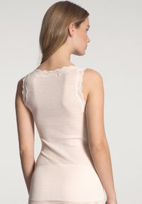 Lichtroze tanktop met een geribbelde textuur, voorzien van een fijne kanten rand langs de schoudernaden en een aansluitend ontwerp.
