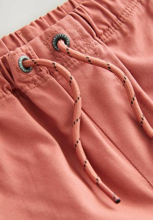 Korte broek in een gedempt koraalkleur, gemaakt van zachte stof met een elastische tailleband, voorzien van een trekkoord met zwarte accenten en metalen ooggaten.
