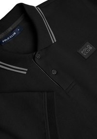 Svart polo skjorta med texturerad tyg, två knappar, en vikbar krage och grå randiga detaljer. Logopatch med "POLO CLUB."