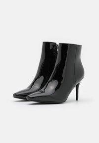 Bottines en cuir verni noir avec bout pointu, fermeture éclair et talon aiguille fin. Texture lisse et finition brillante.