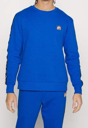 Sweatshirt bleu en mélange de coton, avec un col rond et des poignets côtelés. Bandes latérales noires avec un patch logo sur la poitrine.