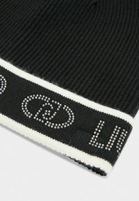Tessuto a maglia nero a coste con bordo bianco caratterizzato dalla scritta "CELINE" in piccoli chiodi d'argento.