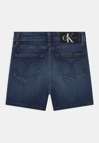 Tummansiniset farkkushortsit klassisella leikkauksella. Varustettu kahdella takataskulla ja Calvin Klein Jeans -tunnuksella vyötäröllä. Rakenteellinen kangas.