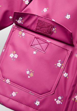 Magenta blomster-mønstret taske med åben klap, der viser velcrolukning og syet forlommer.