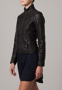 Czarna skórzana kurtka o dopasowanym kroju, ze stójką, pełnym zamkiem z przodu i szczegółowym przeszyciem. Wyposażona w boczne kieszenie.