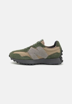 Sneaker basse profil en daim vert olive et beige avec un logo "N" gris texturé et une semelle en caoutchouc noire inclinée vers la gauche.