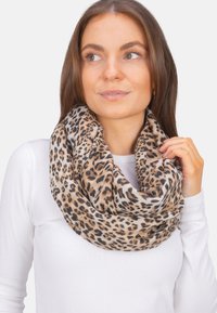 Écharpe à motif léopard en tissu doux, présentant des nuances de marron et de crème. Design en boucle avec une texture visible et des motifs de taches variés.