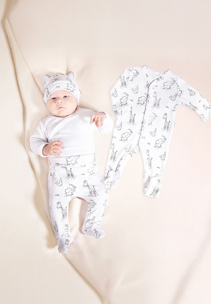 Biały niemowlęcy strój składający się z koszuli z długim rękawem, spodni z wzorem zwierząt oraz dopasowanej czapki z uszami, ułożony na miękkim beżowym tle.