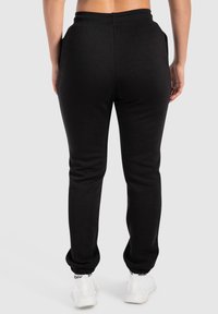 Zwarte sweatpants met een slim fit, elastische tailleband en afgewerkte enkels. Gemaakt van zacht materiaal, met zijzakken en een gladde textuur.