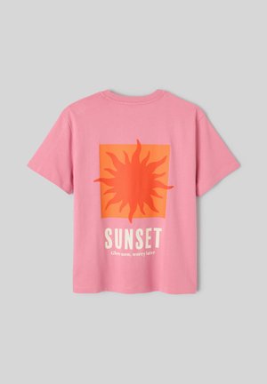 T-shirt rose à manches courtes avec un graphique de soleil orange et le texte « SUNSET Glow now, worry later » au dos, sur un fond gris uni.
