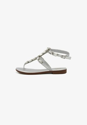 Sandali argento con profilo slim, design a T, gemme decorative trasparenti e suola piatta marrone. Soletta testurizzata per comfort.