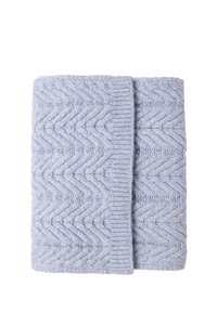 Couverture tricotée bleu clair avec un motif en zigzag et un bord côtelé, pliée soigneusement. Texture douce avec des détails de torsades bien visibles.