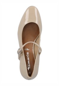 Chaussure Mary Jane en cuir verni beige avec un bout arrondi, une seule bride ajustable et une semelle intérieure texturée.