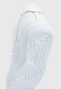 White Nike Air sneaker shown from the sole, featuring circular tread patterns and Nike logo in the center of the outsole.