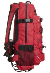 Sac à dos de randonnée rouge avec plusieurs compartiments zippés, sangles noires réglables, poche latérale en mesh et boucles de compression.