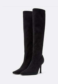 Stivali neri al ginocchio in tessuto morbido con punta appuntita e tacco a stiletto. Dettaglio con zip sul lato interno per una facile indossatura.