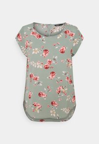 Blumenbluse mit kurzen Ärmeln aus grünem Stoff, verziert mit rosa und roten Rosen sowie Blättern. Rundhalsausschnitt und geschwungener Saum.